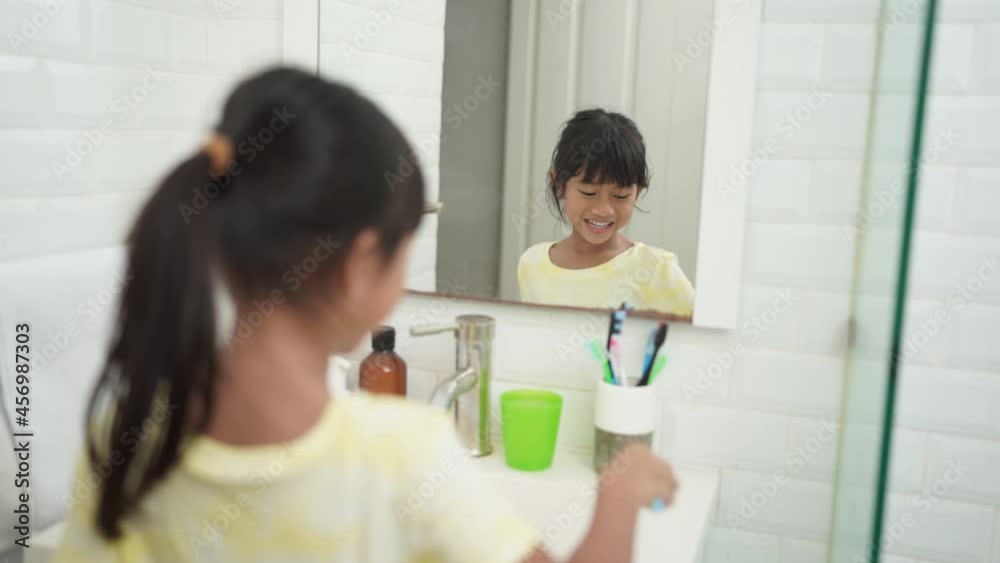 asian little girl brushes her teeth alone in the bathroom asian little girl brushes her teeth alone in the bathroom