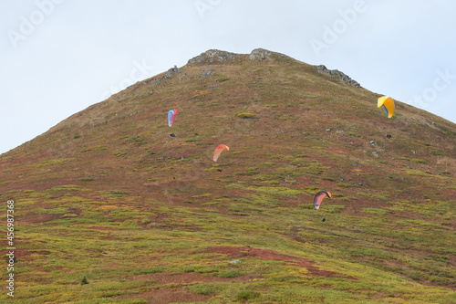 Several paragliders take advantage of a nice autumn day to ride the thermals around a peak in Alaska's Talkeetna Mountains. photo