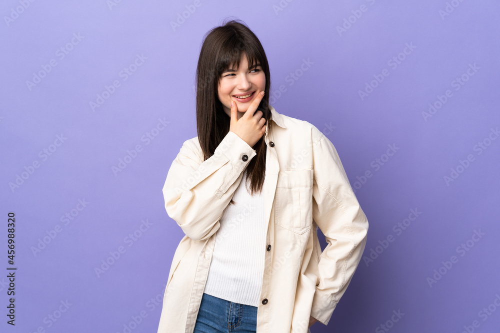 Young Ukrainian woman isolated on purple background looking up while smiling Young Ukrainian woman isolated on purple background looking up while smiling