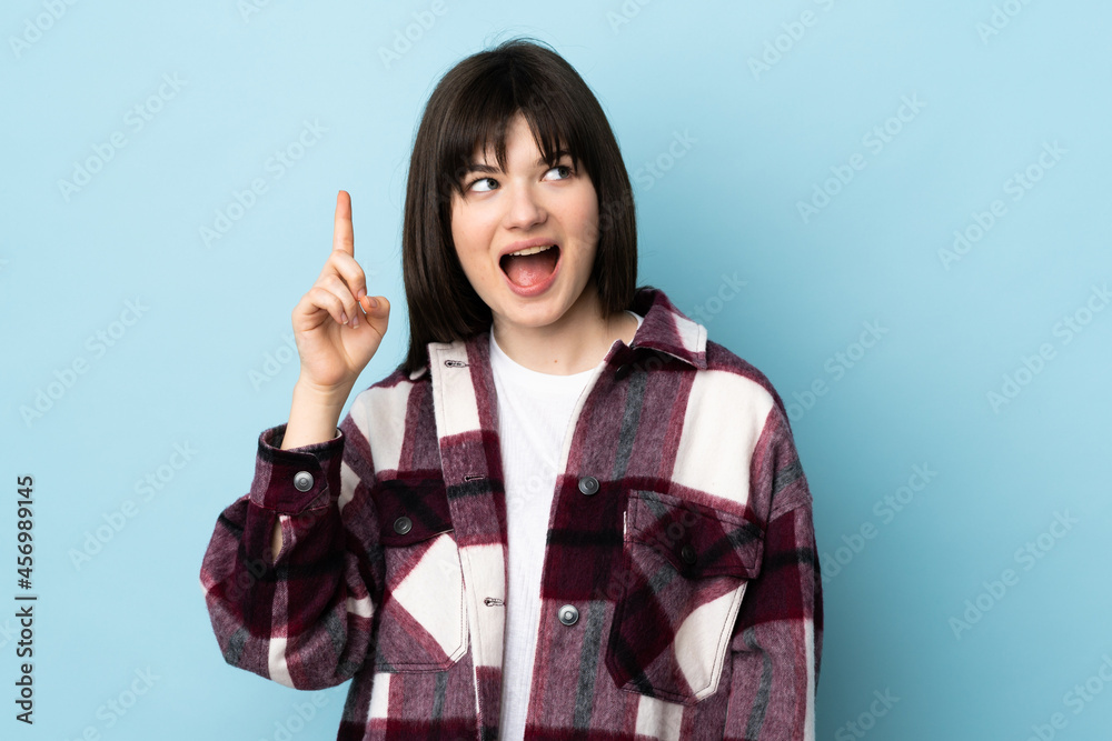 Teenager Ukrainian girl isolated on blue background intending to realizes the solution while lifting a finger up Teenager Ukrainian girl isolated on blue background intending to realizes the solution while lifting a finger up
