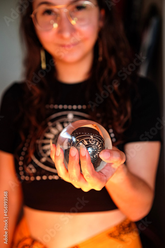 Young spiritual woman full face with a fortune telling crystal ball holding in her hands in warm light  photo