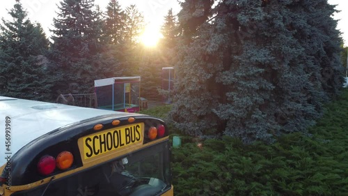 School bus parked at entrance of public school building. Aerial drone overhead shot. photo