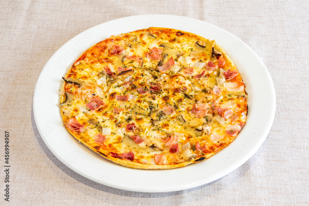 Pizza cooked with carbonara recipe with pieces of smoked bacon, oregano, mushrooms, onion and cream cheese