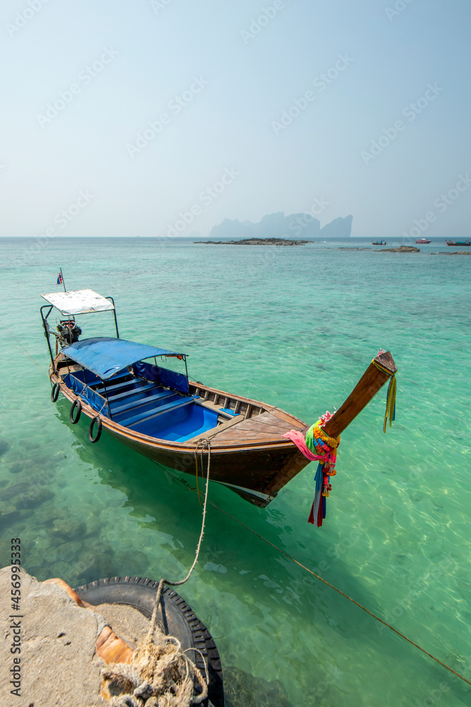 Long-tail boat moored to port on a sunny day with turquoise waters Long-tail boat moored to port on a sunny day with turquoise waters