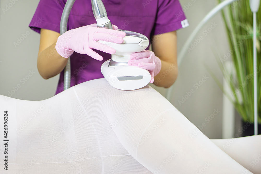 Female body lies on its side in a white suit having anti cellulite LPG