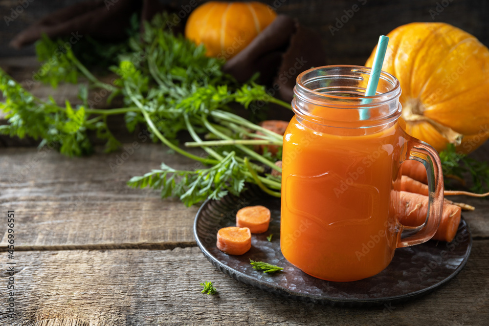 Fresh natural mixed juice, healthy food concept. Glass jar of fresh carrot juice with fresh carrots and pumpkin on a wooden rustic table. Copy space. Fresh natural mixed juice, healthy food concept. Glass jar of fresh carrot juice with fresh carrots and pumpkin on a wooden rustic table. Copy space.
