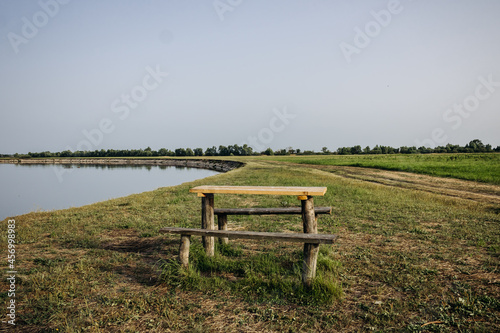 Beautiful summer landscape by the river. Wooden table and benches by the river. Pripyat river, Belarus