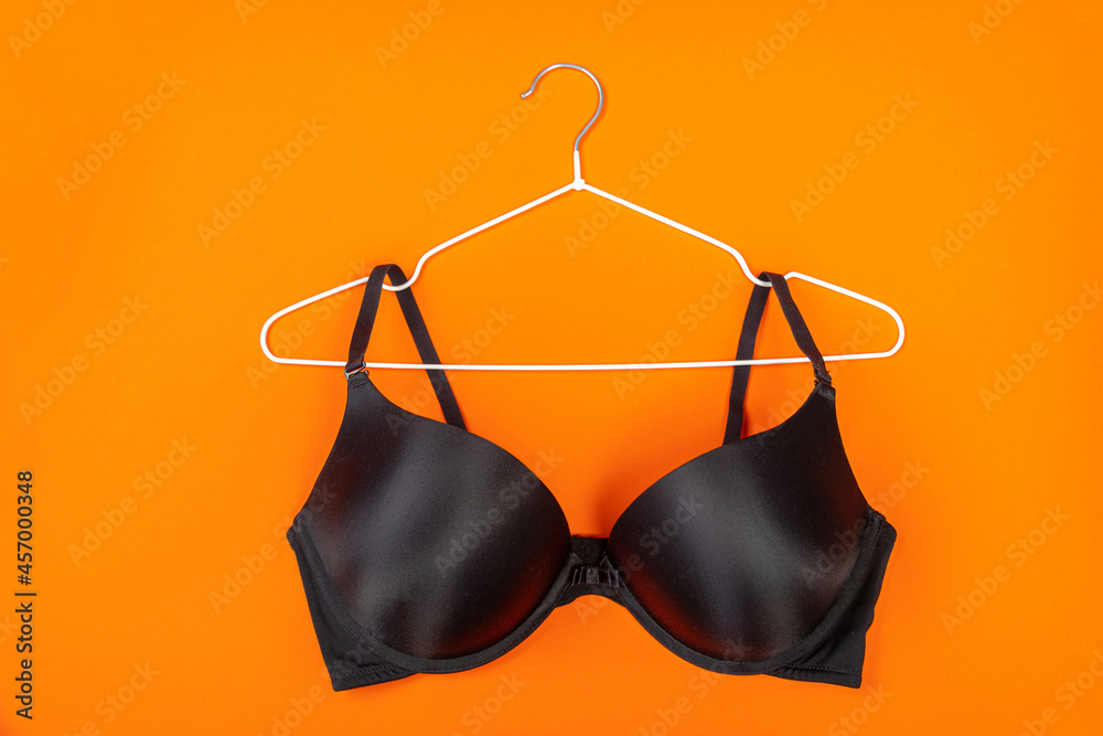 Top view of stylish women bra on white hanger on orange background with copy space. Women's wardrobe Top view of stylish women bra on white hanger on orange background with copy space. Women's wardrobe
