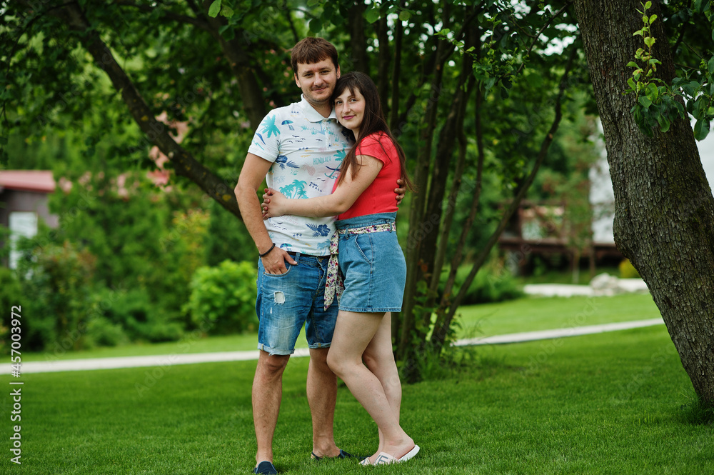 Couple in jeans shorts pose feel love in green grass at courtyard. Couple in jeans shorts pose feel love in green grass at courtyard.