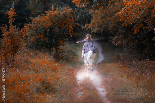 Image of a girl riding a horse in a forest during fall at sunset