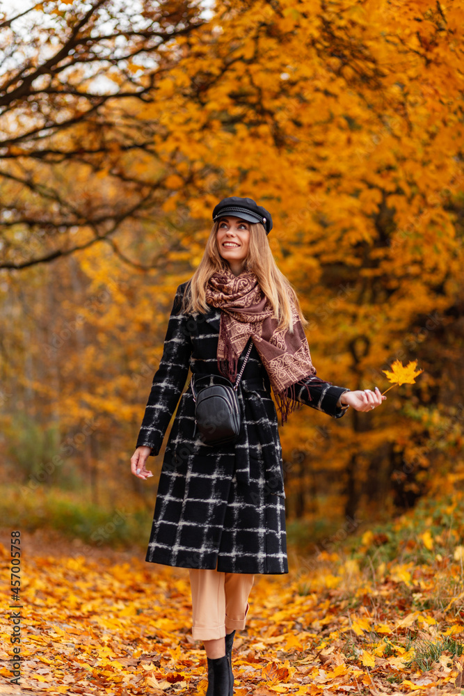 Smiling pretty girl with yellow leaf walks in autumn park with fall leaves Smiling pretty girl with yellow leaf walks in autumn park with fall leaves