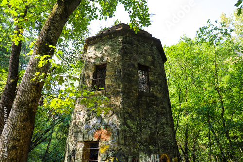 a stone cylinder shaped building in the forest covered with colorful graffiti surrounded by lush green trees and plants at Lullwater Preserve in Decatur Georgia USA photo