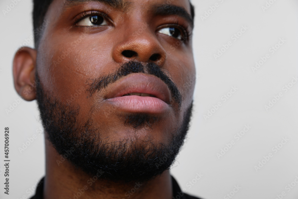 Fototapeta premium Cropped portrait of handsome muscular black man looking a side on white wall.