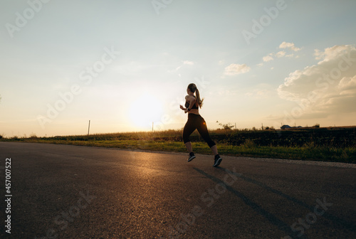 Young sporty girl running on a  road at sunset.   Lifestyle sports motivation.  © Miha Creative
