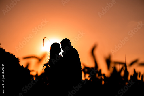 silhouette of a couple on a sunset background, a slender girl stands near a man, horizontal image.