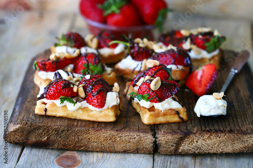 French waffles with strawberries and chocolate, cream cheese and nuts.
