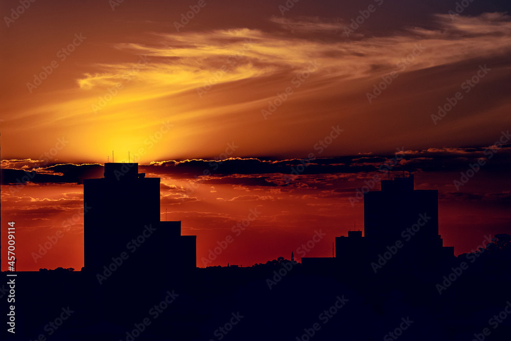 Silhueta da paisagem urbana de São Carlos São Paulo com o céu colorido de laranja e amarelo devido ao por do Sol