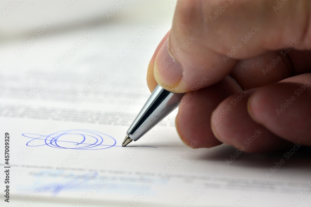 Detalle de una mano con un bolígrafo firmando un documento Detalle de una mano con un bolígrafo firmando un documento