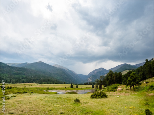 Scenic view of marsh, forest, and Rocky mountains with storm rolling in.