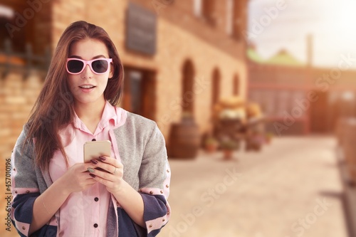 Portrait of girl looks surprised and excited at smartphone screen or mobile phone,