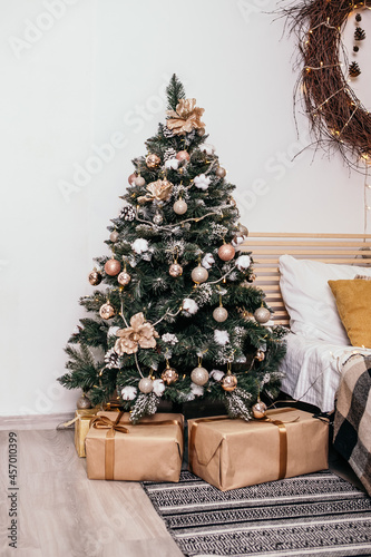 Cozy flat apartment room with green Christmas Tree gifts presents on carpet garlands, candles decorated interior New Year beautiful living room in the evening, lights glowing