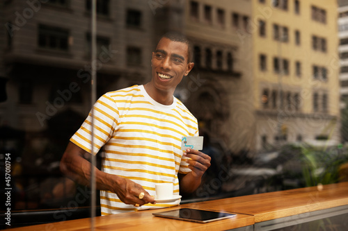 Handsome young african man in cafe drinking coffee. Portrait of happy man with credit card drinking coffee in cafe..
