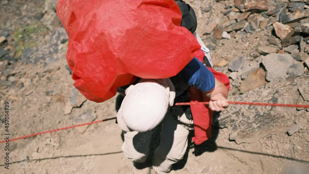 Vidéo Stock A man on the rocks goes down holding on to a rope on a ...