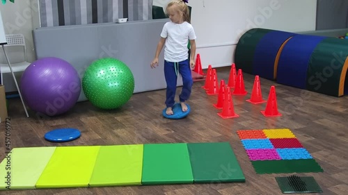 Child with sensory disorders performs exercises in the sensory integration room. Development of all the senses with special therapeutic exercises photo