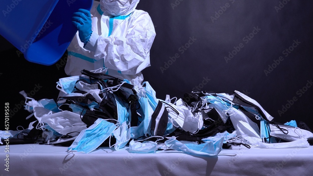Recycle worker in gloves, sorting medical masks in the recycle bin