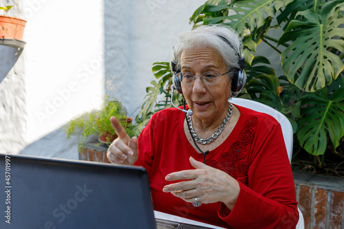 Elderly lady connected to laptop, taking classes, working or making a video call with her grandchildren. Lifestyle of modern elderly people.