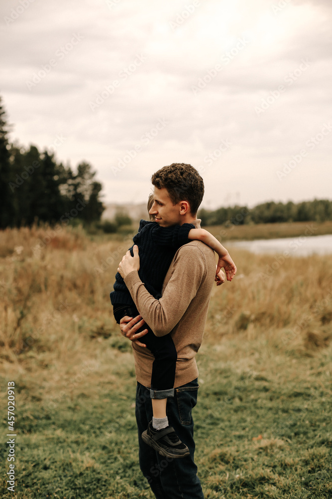 a young man holds his little son in his arms and hugs him
