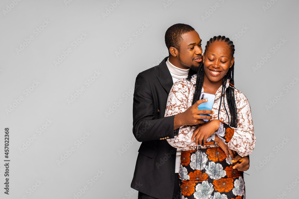 Smiling young black man embracing woman from behind while looking at ...