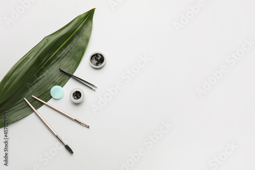 Tropical leaf, henna and tools for eyebrows correction on light background photo