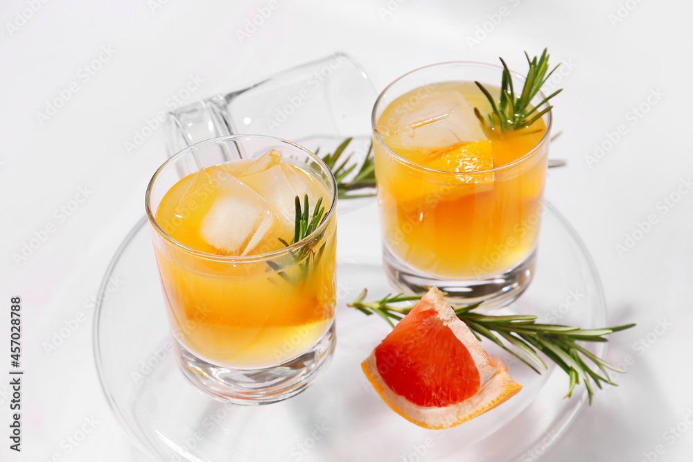 Glasses of tasty grapefruit cocktail with rosemary on white background Glasses of tasty grapefruit cocktail with rosemary on white background