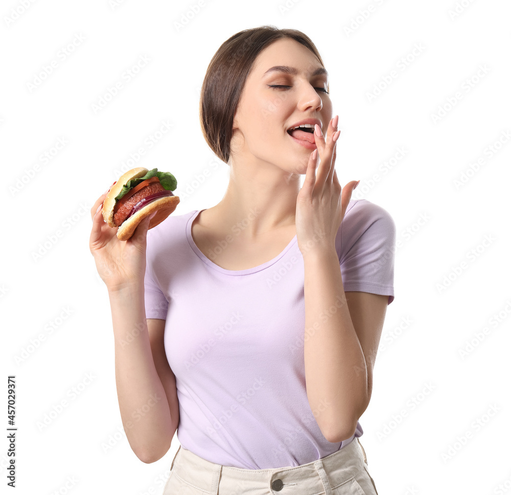 Beautiful young woman eating tasty vegan burger on white background Beautiful young woman eating tasty vegan burger on white background
