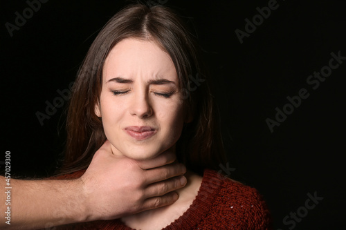 Bild auf Leinwand Man holding young woman by throat on dark background