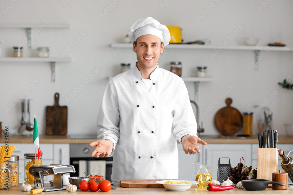 Italian chef near table with delicious food in kitchen Italian chef near table with delicious food in kitchen