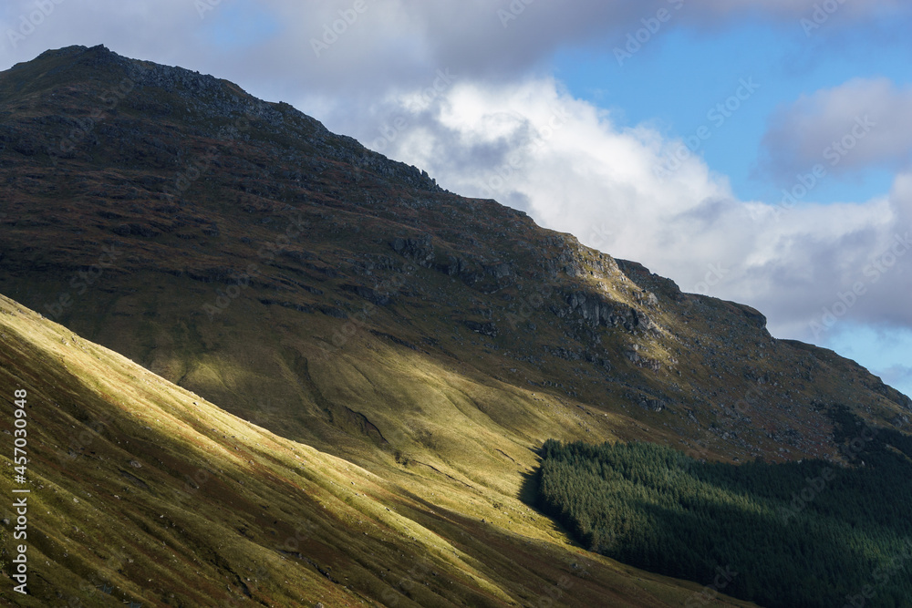 Mountain touched by golden sunlight in beautiful landscape with forest, Scotland