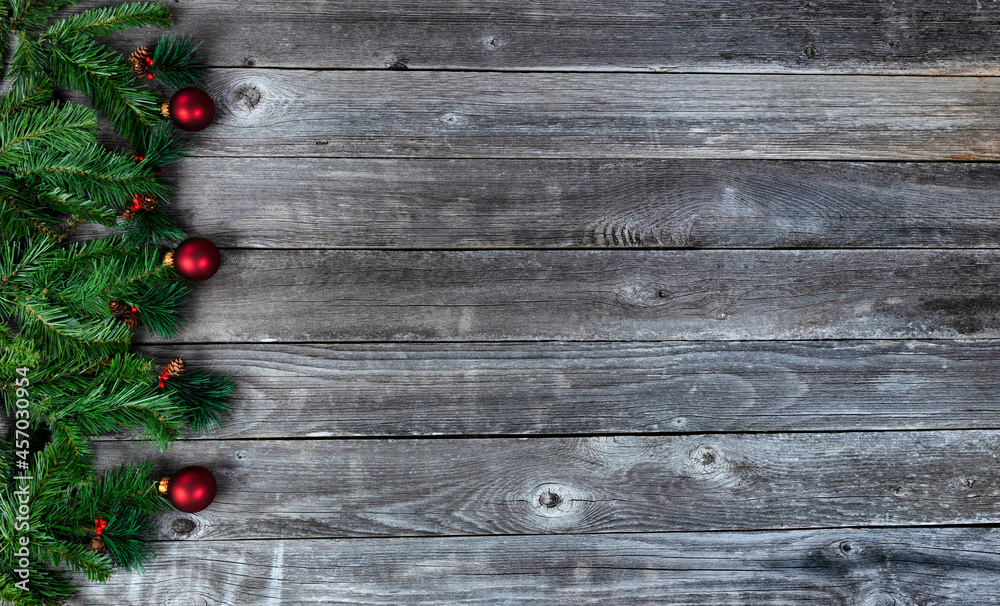 Fir tree branches and red ornaments on wood planks for a merry Christmas or happy New Year holiday celebration concept Fir tree branches and red ornaments on wood planks for a merry Christmas or happy New Year holiday celebration concept
