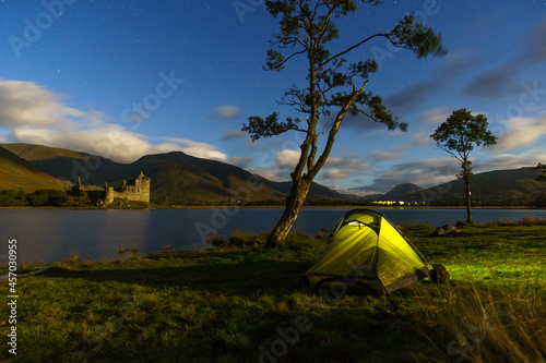 View at Kilchurn Castle illuminated by the moon light at Night with tent, Loch Awe, Scotland