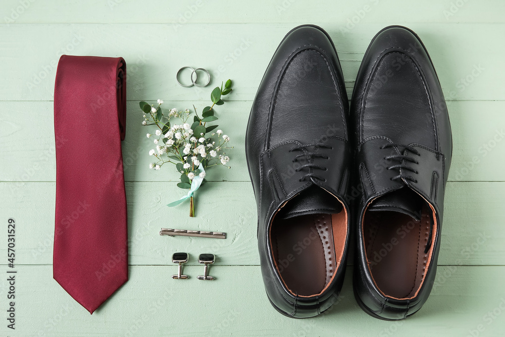 Wedding rings and stylish groom accessories on green wooden background Wedding rings and stylish groom accessories on green wooden background