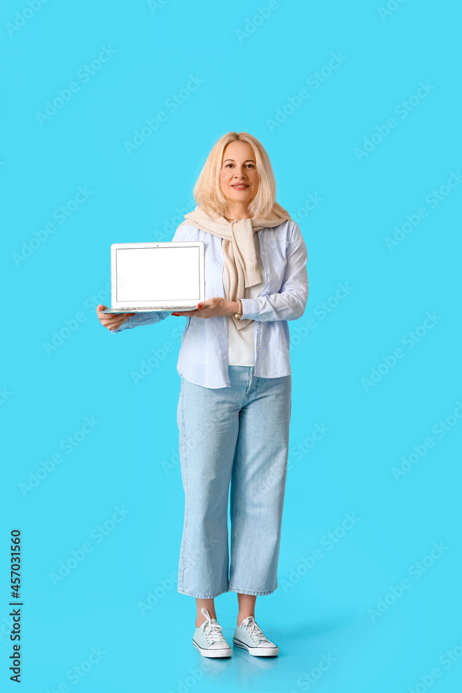 Fototapeta premium Portrait of mature woman with laptop on color background