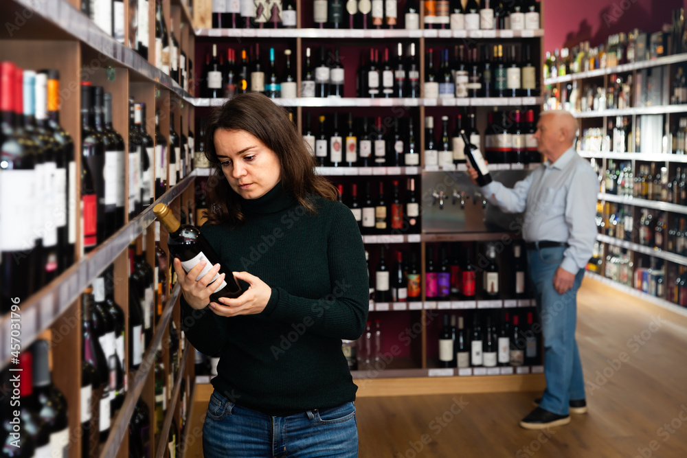Portrait of woman customer buying bottle of wine in liquor store