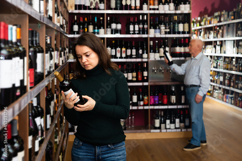 Portrait of woman customer buying bottle of wine in liquor store