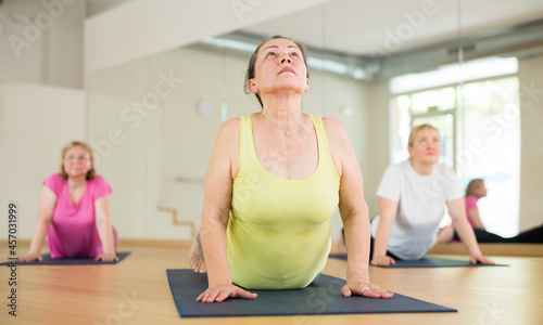 Mature women practicing yoga training - pose bhujangasana