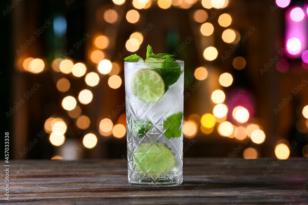 Glass of cold mojito on table against blurred lights Glass of cold mojito on table against blurred lights