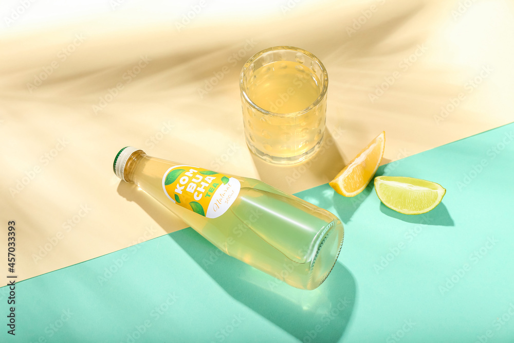 Glass and bottle of fresh kombucha tea with citruses on color background Glass and bottle of fresh kombucha tea with citruses on color background