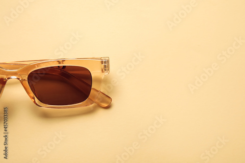 Stylish female sunglasses on color background, closeup
