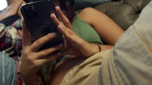 Young people are stuck in phones sitting next to each other on the sofa