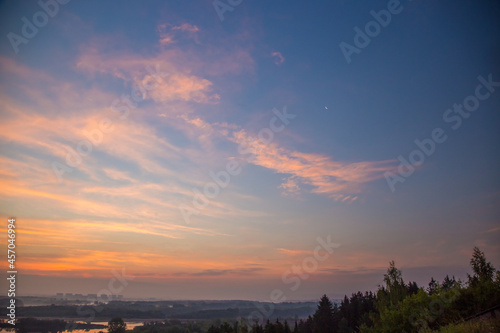 light clouds in the sky shimmer with bright colors at dawn on a warm summer morning © Dmitrii